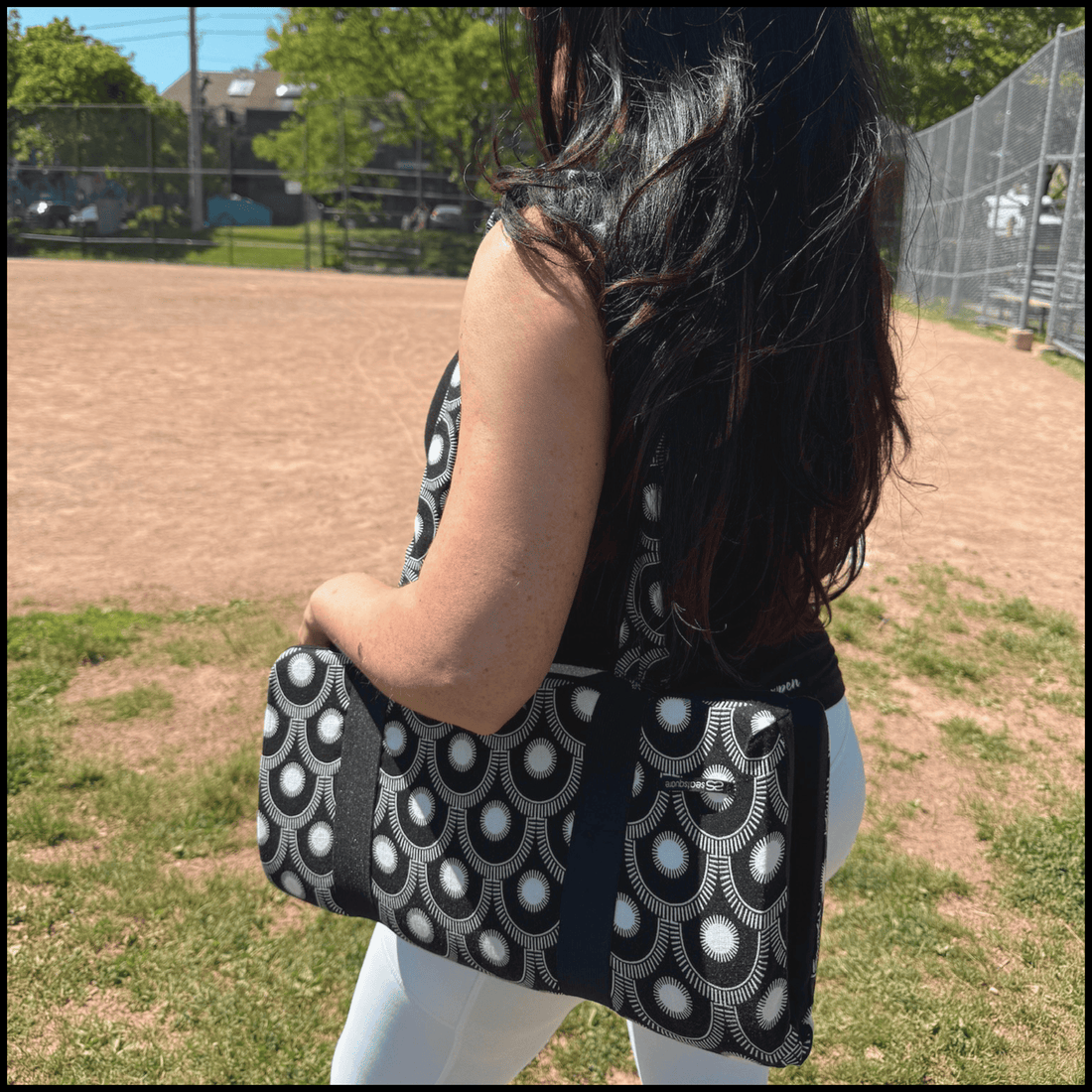a stylish seat cushion with a black and white geometric pattern on a metal bleacher at an outdoor baseball diamond
